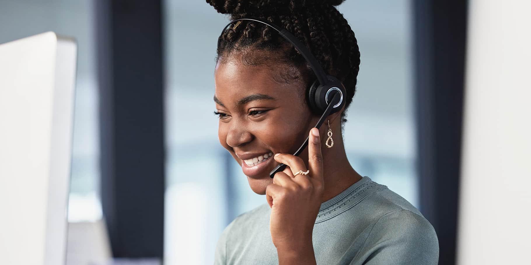 A smiling young African American woman on a phone headset.