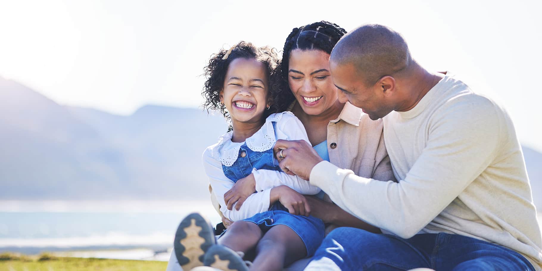 A smiling young girl with her mother and father.