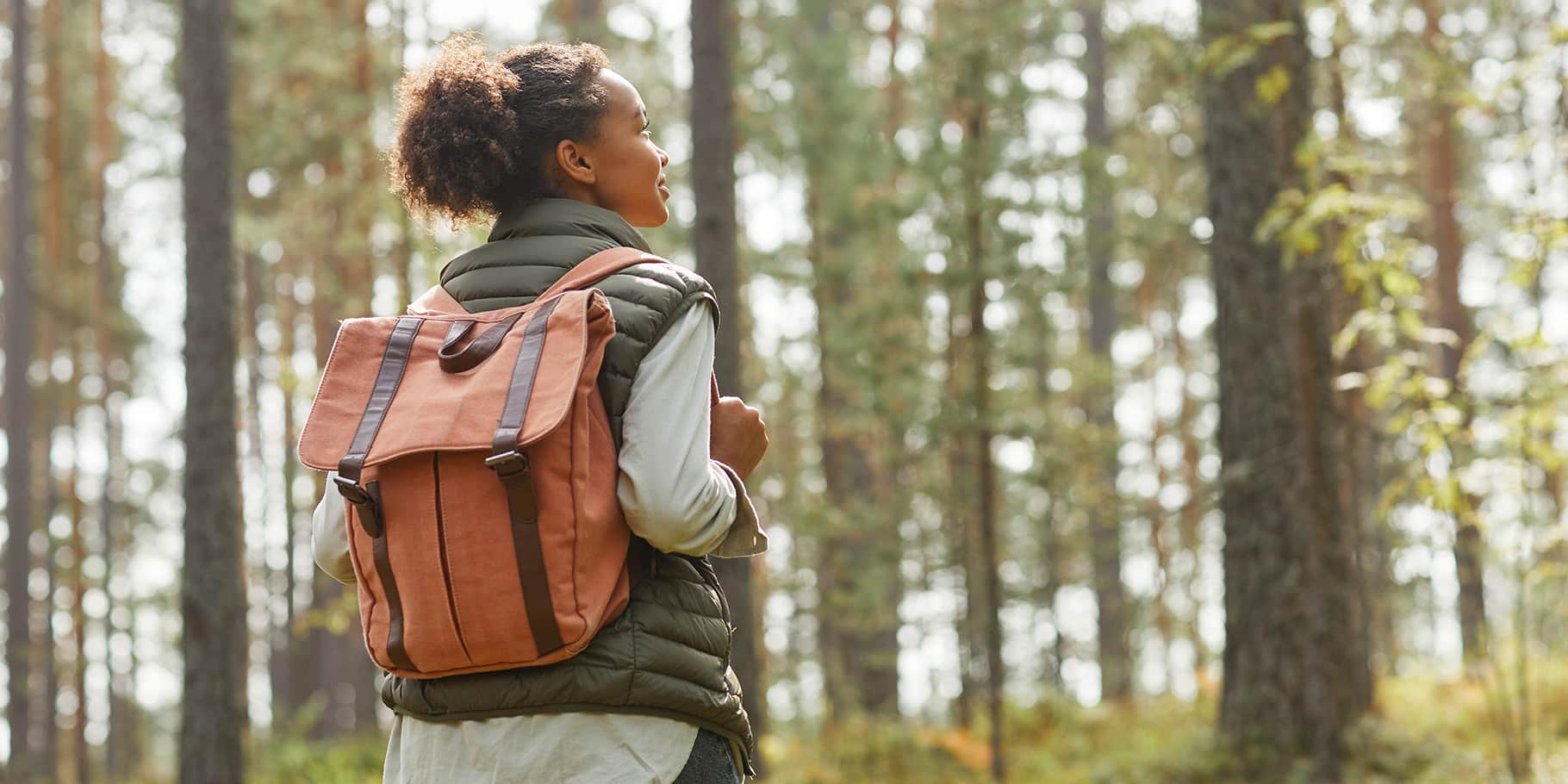 A female student gazing up towards trees.