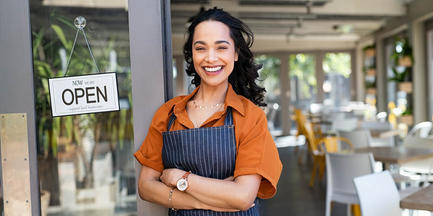A young waitress smiling at the entrance of a restaurant.