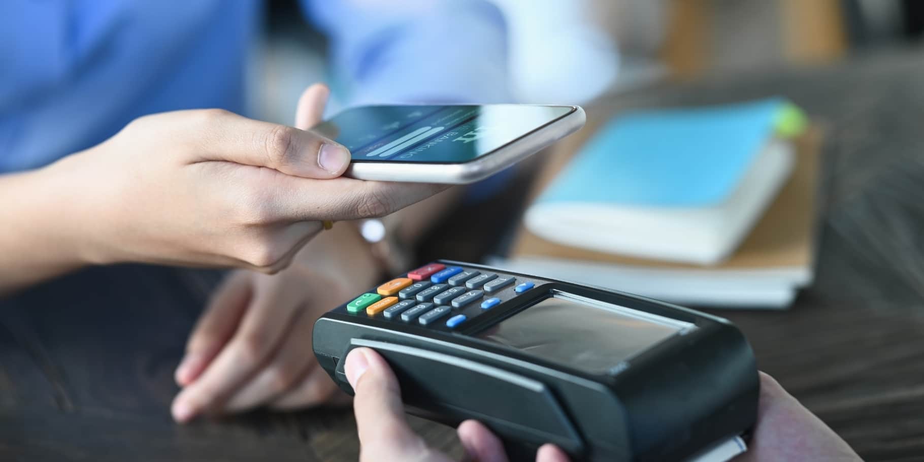 A male hand holding a mobile phone to make a payment.